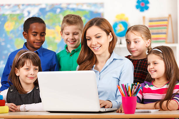 istock Teacher And Students In Classroom With Laptop 472176735