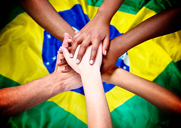 istock Six mixed hands piled in support over Brazilian national flag 472177123