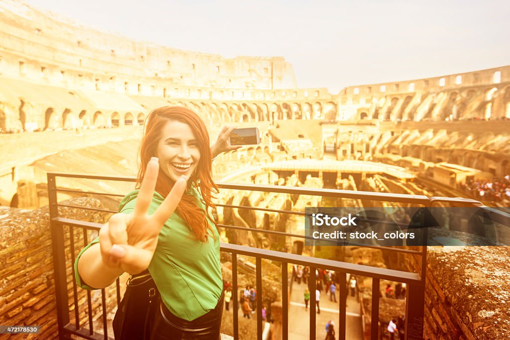 so happy in Rome happy woman showing peace sign and making photos with her smart phone at Colloseum. 2015 Stock Photo