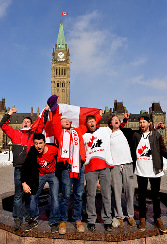 Ottawa, Canada – February 23, 2014:  Canadians sing national anthem on Parliament Hill in Ottawa at 10:06 am to celebrate Canada's defense of Olympic hockey gold with a 3-0 win over Sweden in the final game.  The game started at 7 am local time.