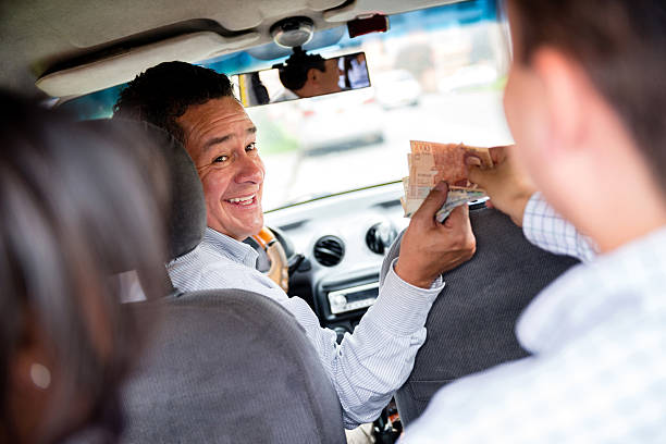 Couple paying for the taxi Couple paying for the taxi driver in cash cash in transit vehicle stock pictures, royalty-free photos & images
