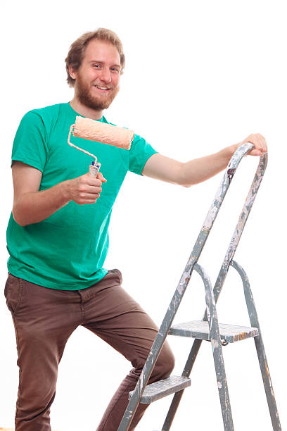 istock Bearded man painting on a ladder 472180408