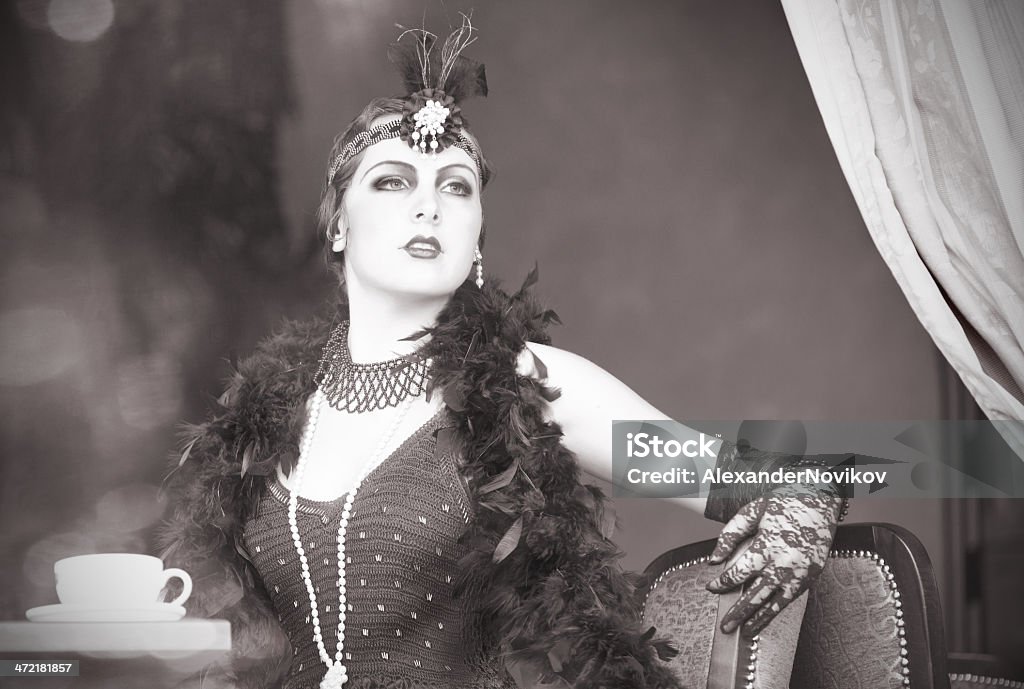 Retro Woman 1920s - 1930s Sitting with Cup of Tea Black and White Portrait of The Beautiful Retro woman Drinking Tea in the Cafe in Black Lace and Accessories  in Style 1920s - 1930s  Flapper Style Stock Photo