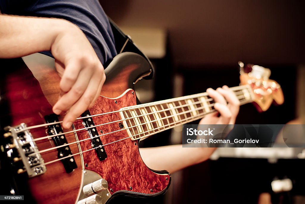 A man playing a guitar in a room musician playing a bass guitar Bass Guitar Stock Photo