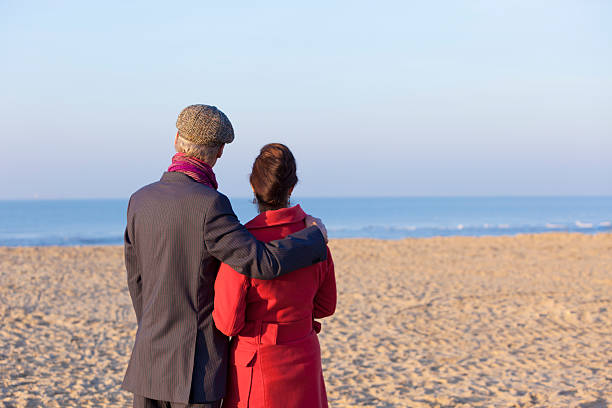 Mid aged couple looking at beach Mid aged couple looking at beach   scene40 stock pictures, royalty-free photos & images