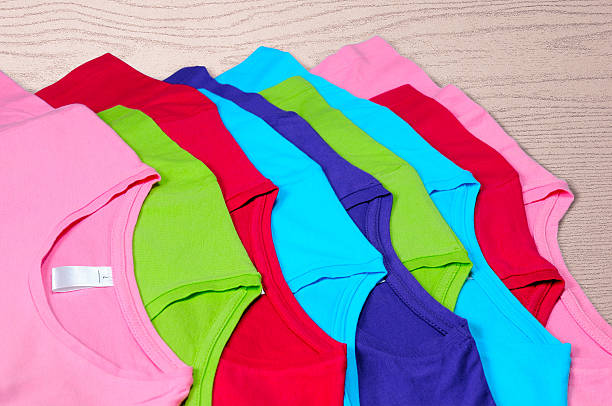istock Multi-colored women's t-shirts lie on wooden background 472185602