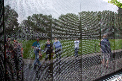 Washington, USA - July 14, 2010: Names of Vietnam war casualties on Vietnam War Veterans Memorial in Washington DC, USA. Names in chronological order,from first casualty in 1959 to last in 1975. People visit the memorial.