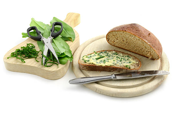 herb butter wild garlic (Allium ursinum) on bread cutting wild garlic leaves for herb butter. in background a heab scissors on white isolated background zigeunerlauch stock pictures, royalty-free photos & images