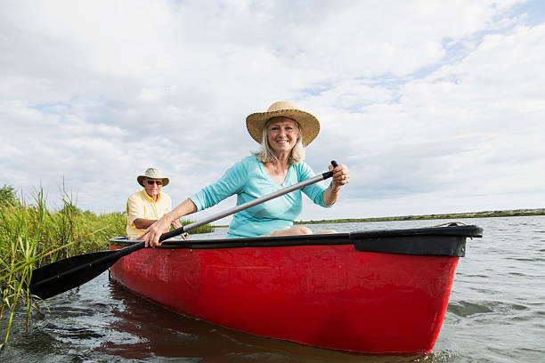 Low angle view of active senior couple canoeing.  Woman is in front of canoe with oar.