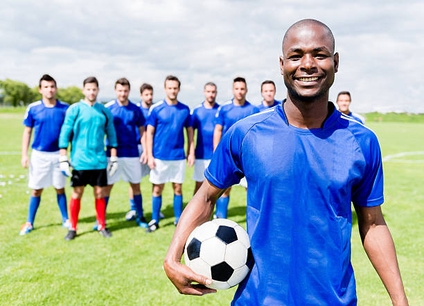 Happy football player Happy football player with his team at the soccer field soccer team captain stock pictures, royalty-free photos & images