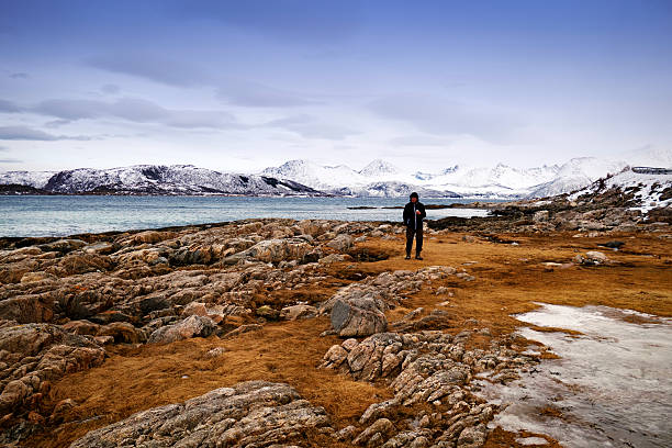 istock Man standing on a rocky beach in winter, Norway 472190872