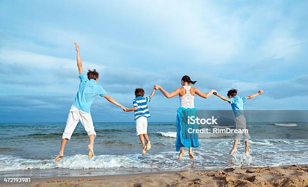 Mother And Three Sons Are Jumping On Beach Stock Photo - Download Image Now - Adolescence, Adult, Beach