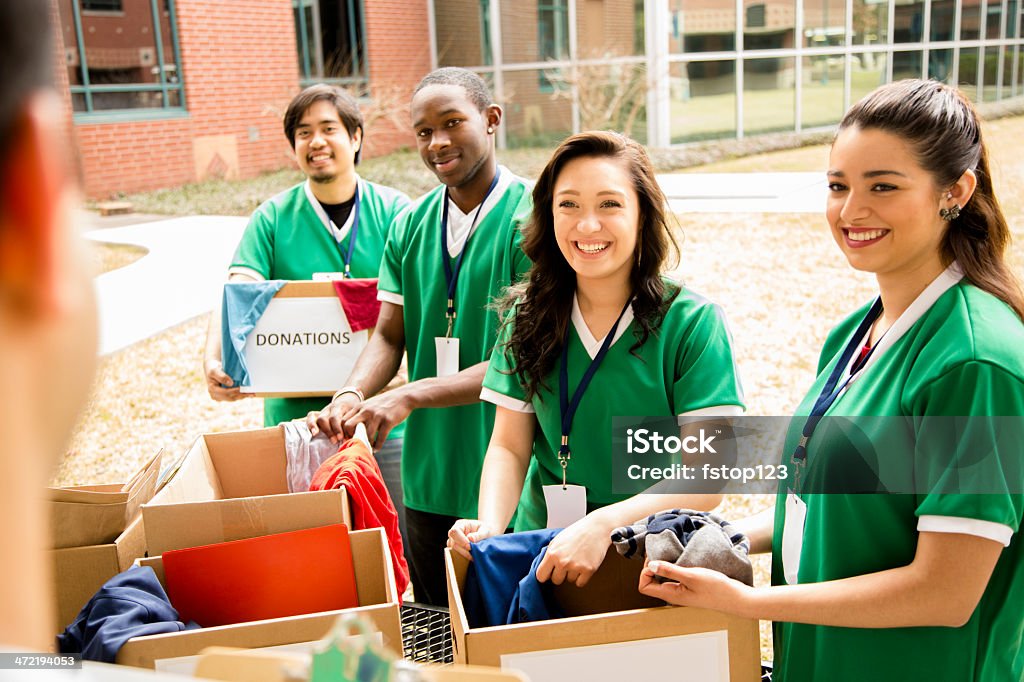 Volunteers: College students collect clothing donations for community. Organized group of multi-ethnic college student volunteers collect clothing donations for needy families in their community.  Over shoulder view of team leader with clipboard.  Emergency Management Stock Photo