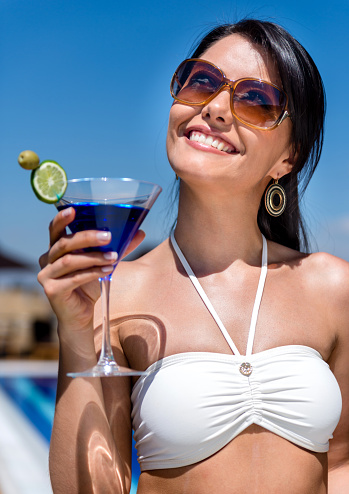 Portrait of a happy woman holding a martini and enjoying vacation time