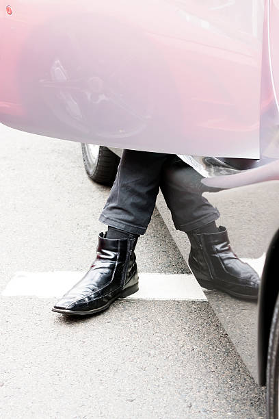 Closeup male leg with leather boot stepping out of the car, full frame vertical composition with copy space,