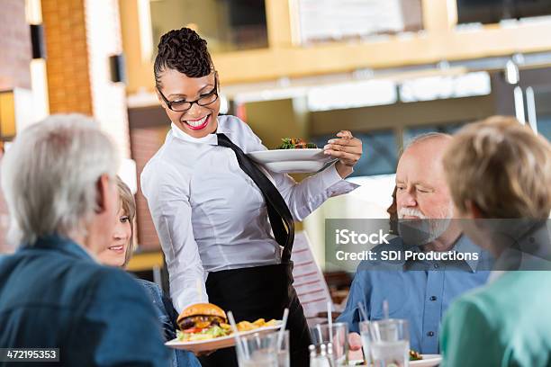 Waitress Delivering Food To Customers Table In Modern Restaurant Stock Photo - Download Image Now