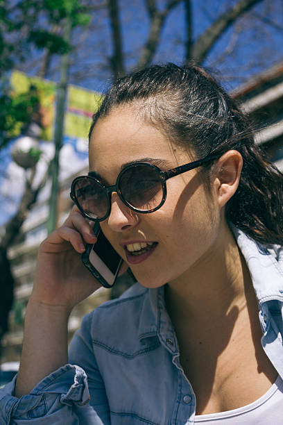 istock Young beautiful woman with sunglasses talking with her phone sit 472196692