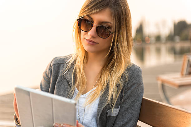istock Young beautiful girl with tablet against lake 472196904