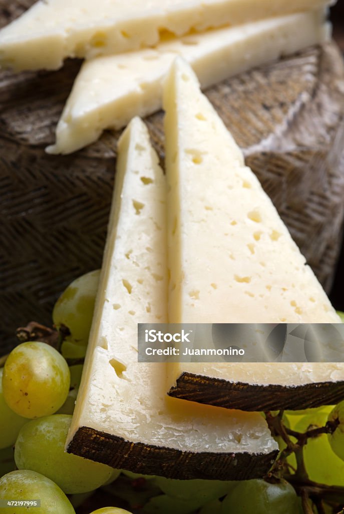 Spanish Manchego Cheese Macro image of few slices of spanish cured manchego cheese and grapes Appetizer Stock Photo