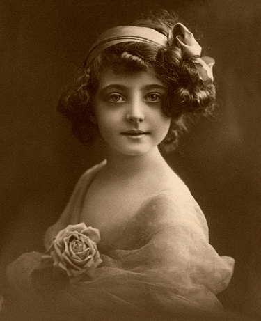 Portrait of a young woman. She sits on a luxurious chair that has fallen over and stretches her legs.