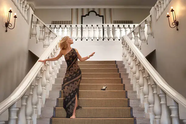 A young woman losing a shoe while running down a magnificent staircase