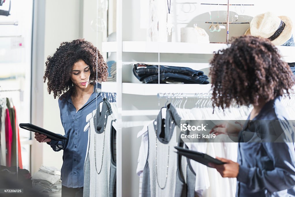 Woman in boutique with digital tablet Young woman (19 years) in clothing store, holding digital tablet. Technology Stock Photo