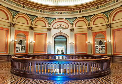 Sacramento, California, USA - April 30, 2015: This second floor of the California State Capitol give you an entrance to the hallway the provides access to the State Senator offices on the right and the State Assembly Members on the left and you can see many insignificant people in the hall way most likely conducting business of the State. The hole in the floor with the beautiful railings offers view to the overhead Dome as well and the rotunda of the Capitol Building on the floor below and on this colorful beautiful April day all was great.