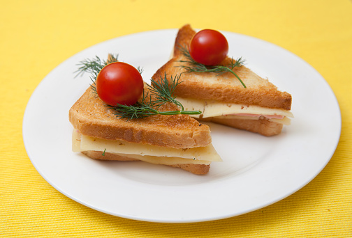 Triangular toast with cheese and ham on white plate
