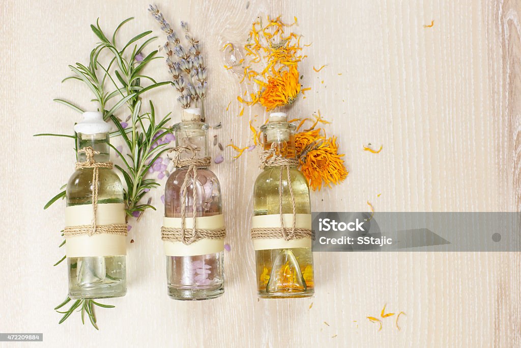 Aromatherapy massage oils Essential oils for aromatherapy and massage.  Row of essential oils in glass bottles, rosemary, lavender and calendula, on the wooden board. Aromatherapy Stock Photo