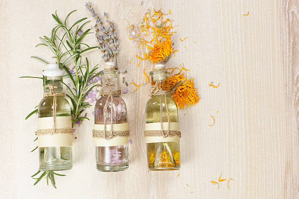 Aromatherapy massage oils Essential oils for aromatherapy and massage.  Row of essential oils in glass bottles, rosemary, lavender and calendula, on the wooden board. botanical spa treatment stock pictures, royalty-free photos & images