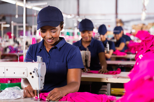 young african textile worker sewing on production line