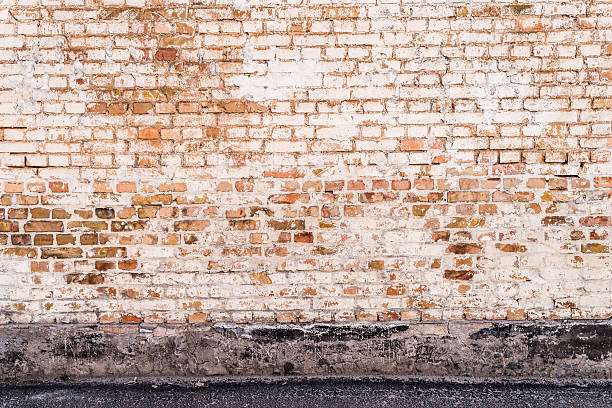 istock Aged grunge brick wall with part of asphalt road 472214278