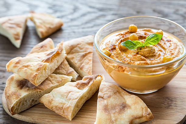 schüssel mit hummus mit pita-scheiben - pita stock-fotos und bilder