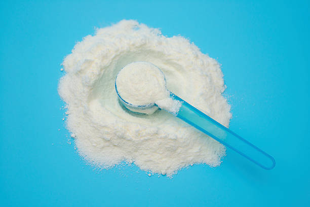 istock powdered milk in a blue spoon on blue background, closeup 472218518