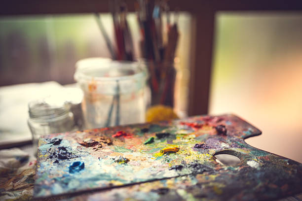 istock Paint-filled artists palette with brushes in the background 472219483