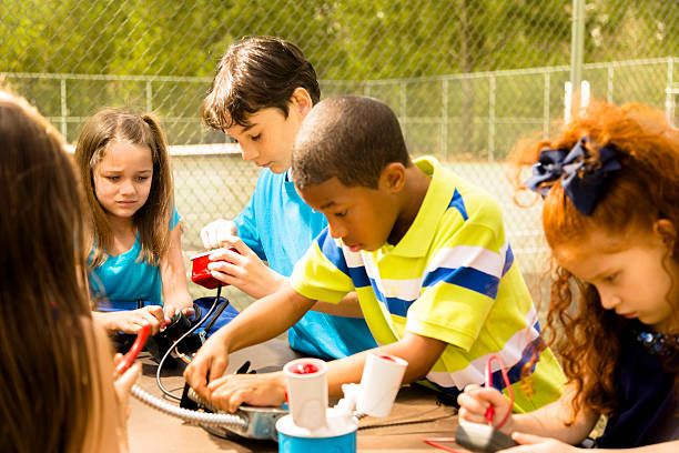 istock Little engineers!  Ethnic elementary children collaborate on 'robot' they created. 472221199