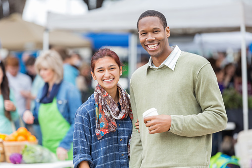 Cute diverse couple spending morning together at local farmers market. 