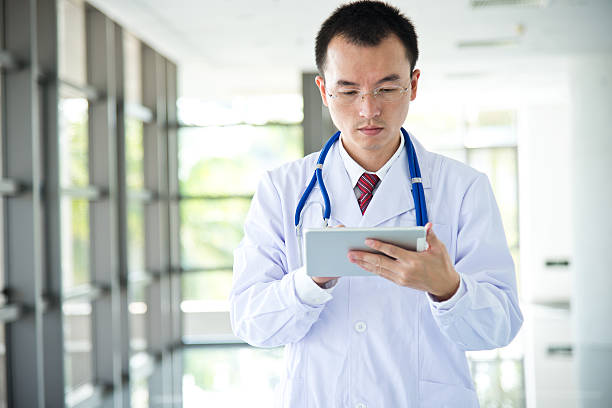 istock Asian doctor writing on a clipboard in an office building 472224089