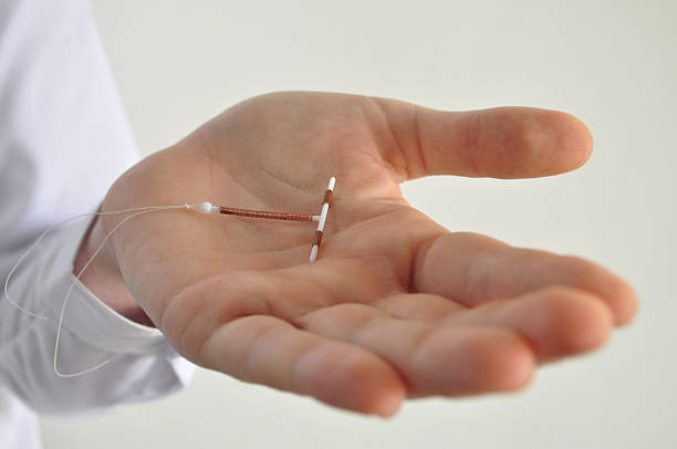 Holding an IUD birth control device in hand Holding an IUD birth control copper coil device in hand, used for contraception - side view family planning stock pictures, royalty-free photos & images