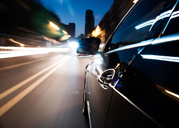 istock Side view of black car driving quickly at night 472225723