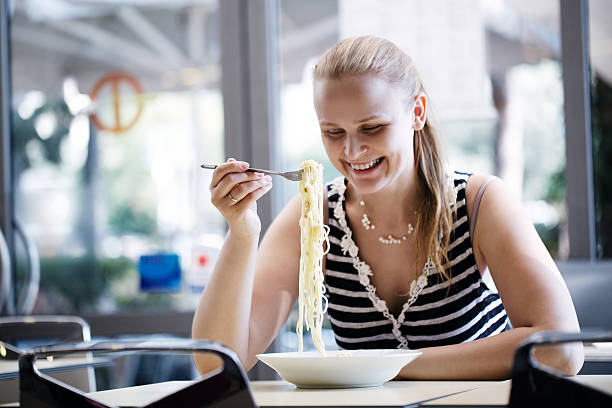 istock Young woman eating spaghetti 472227165