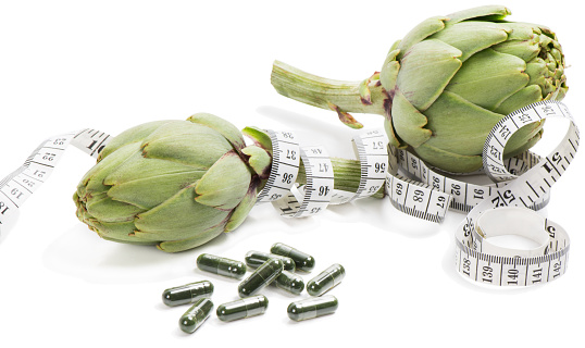 Measuring tape wrapped around a artichokes  as a symbol of diet.  Isolated over white background