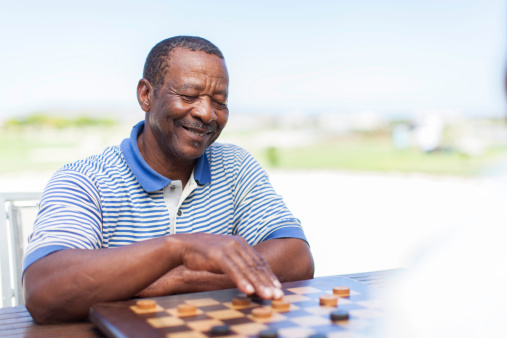 African senior playing chess with a smile, feeling good about his next move. Langebaan, Western Cape, South Africa