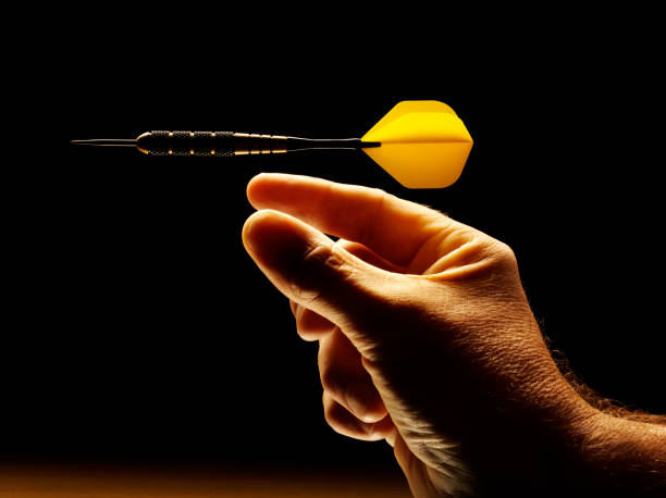 Aiming an Airborne Yellow Dart Aiming an airborne yellow dart on a black background. stars in your eyes stock pictures, royalty-free photos & images