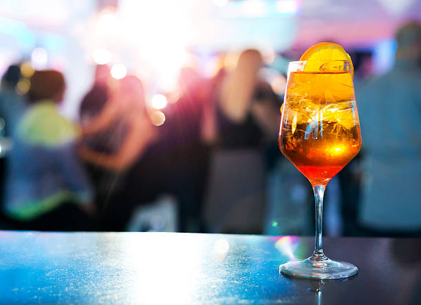 Spritz cocktail Cocktail Spritz garnished with slice of orange, people in background, copy space fruit garnish stock pictures, royalty-free photos & images