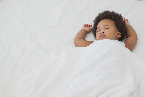 High angle view of a cute little Afro baby sleeping in bed at home