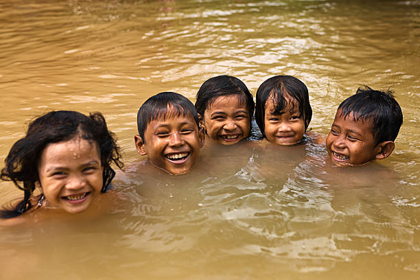 bambini divertirsi in acqua durante l'inondazione, cambogia - flood people asia cambodia foto e immagini stock