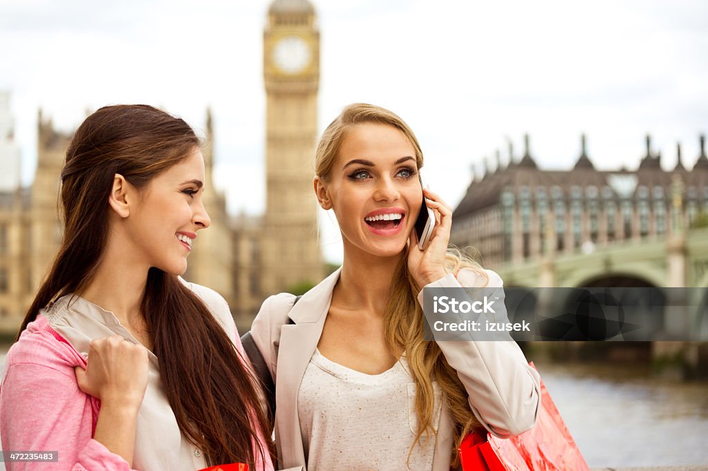 Friends in London Outdoor portrait of two happy London tourists, the blonde talking on phone. House of Parliament and Big Ben in the background. Beautiful Woman Stock Photo