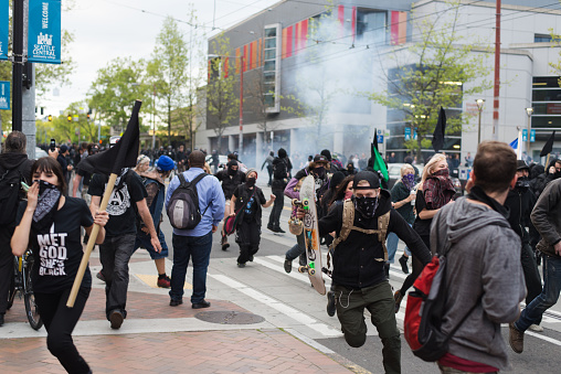 Seattle, WA, USA – May 1, 2015: Protesters run from gas grenades fired by Seattle police officers during May Day rioting on Capitol Hill.