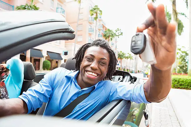 Photo of Man holding out keys while in convertible